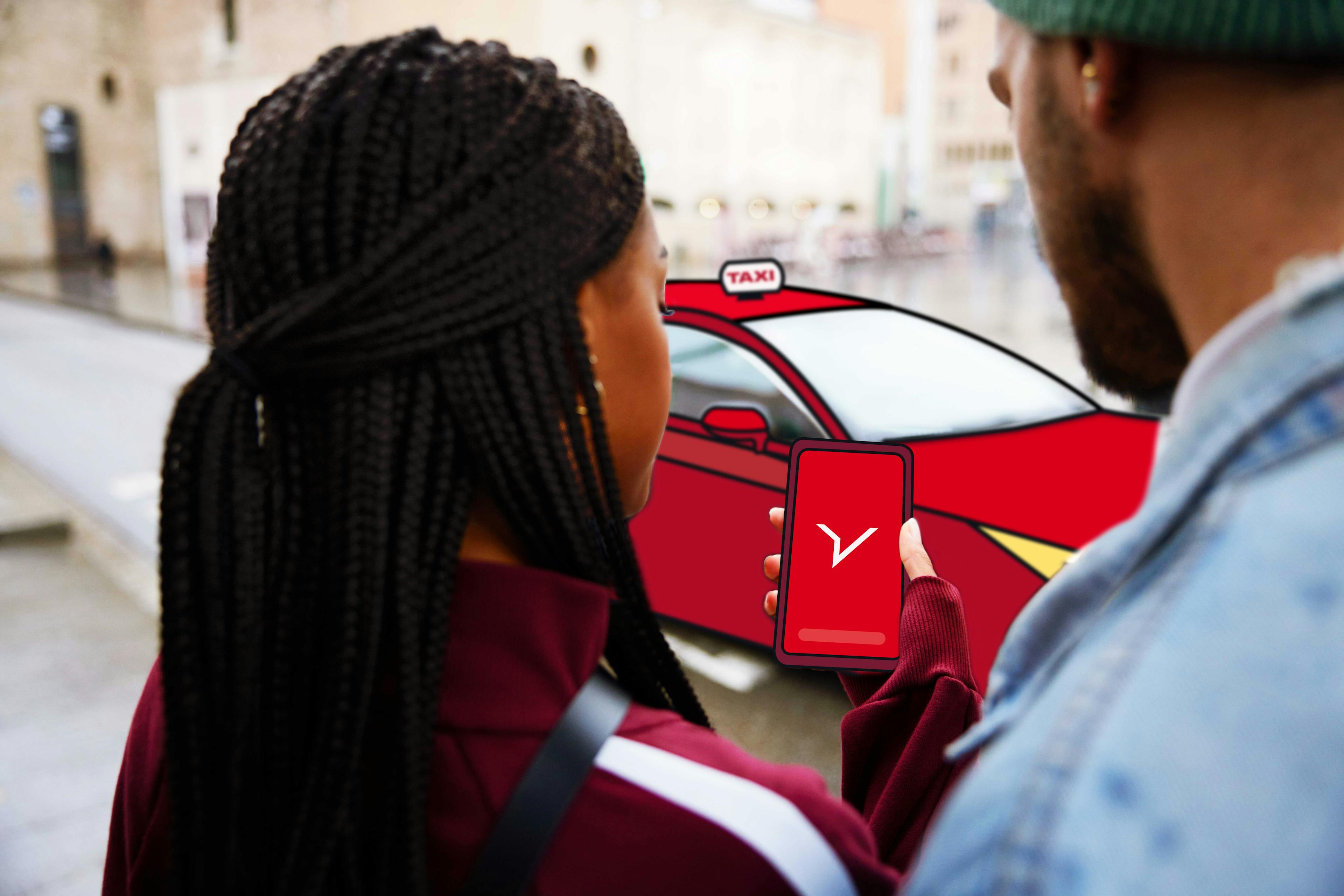 Dos viajeros de negocios miran un teléfono con el logotipo de FREENOW mientras se detiene un taxi rojo.