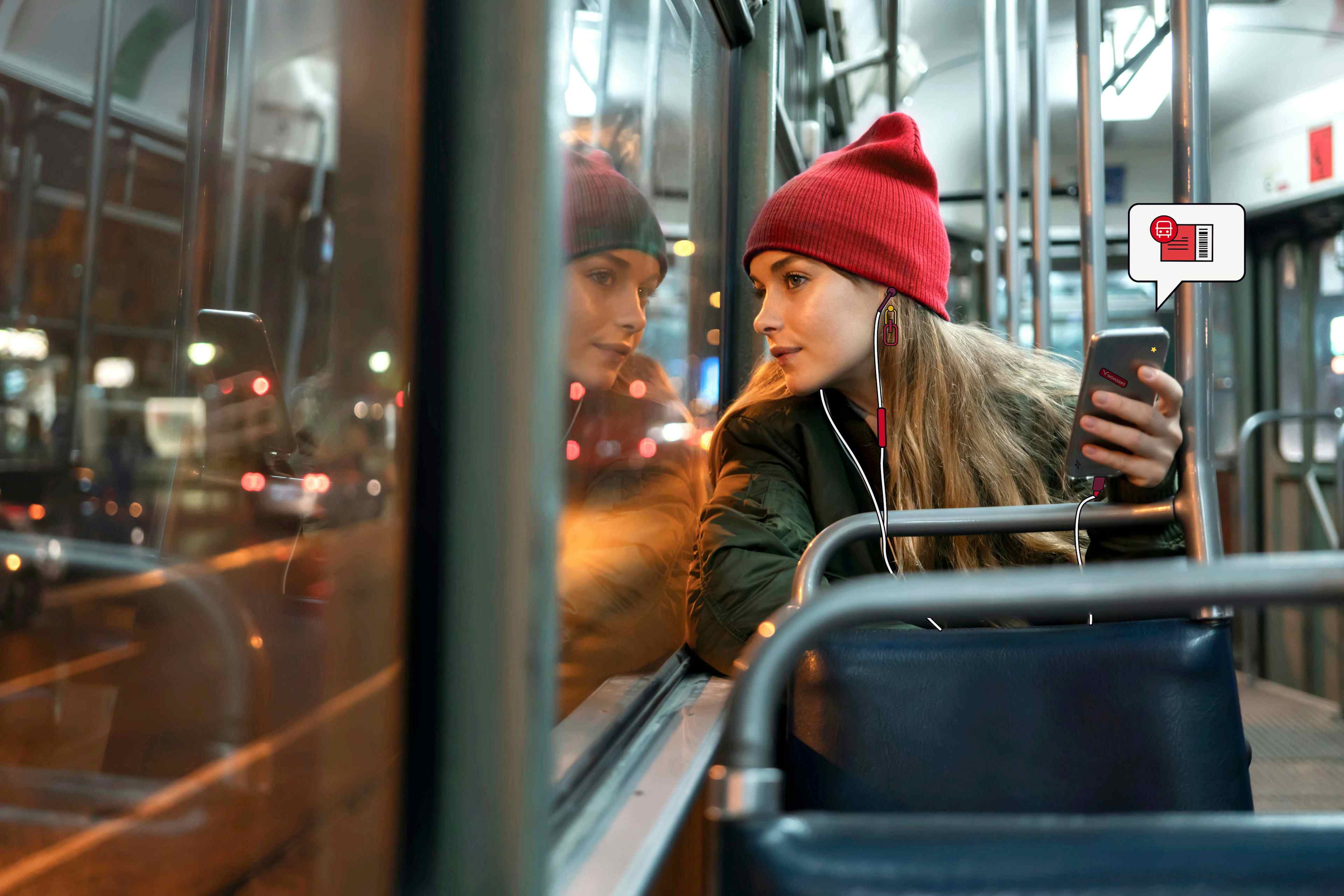 Impiegata in autobus che tiene in mano il suo telefono con l'icona di un biglietto del trasporto pubblico che spunta fuori dal cellulare